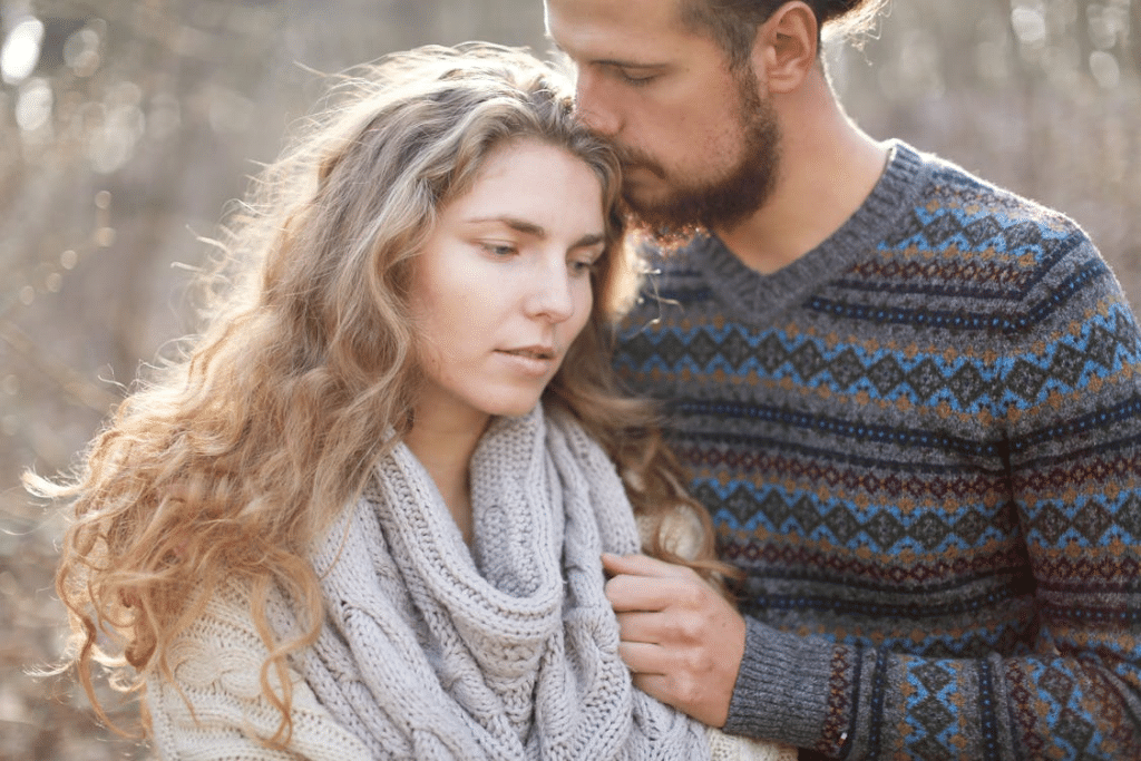 A Bearded Man Smelling the Head of a Woman in Knit Wear