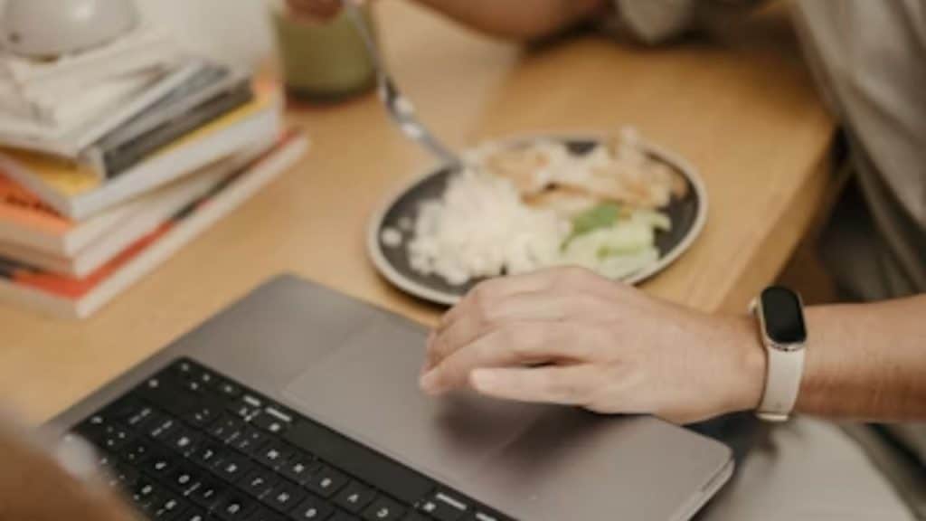 A man avoiding a shared dinner table by staying on his laptop