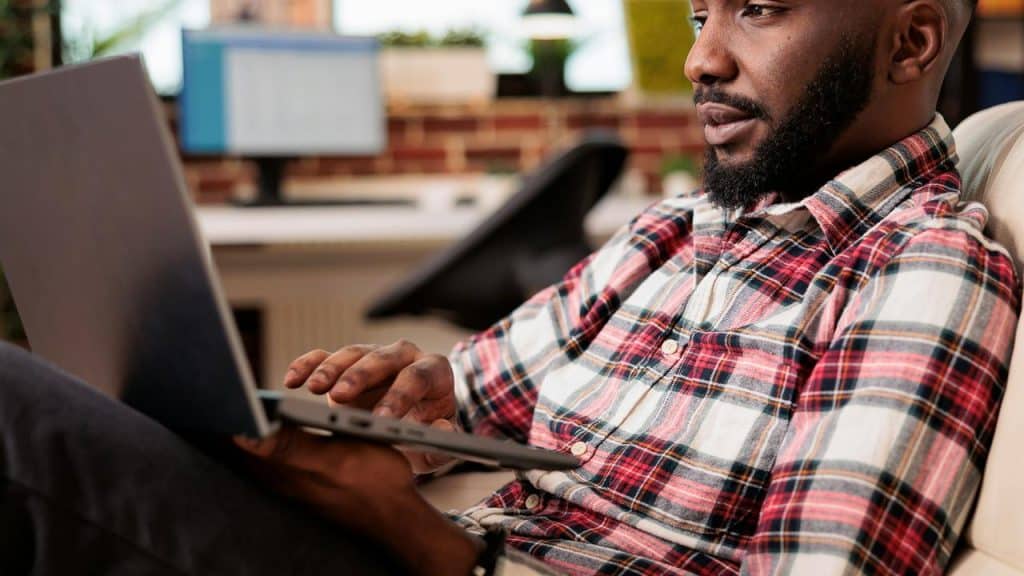 A man in a plaid shirt using a laptop in an office.