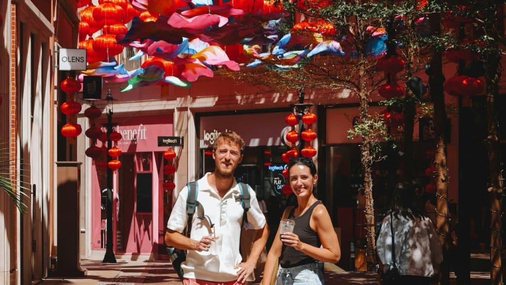 A couple standing on a street decorated with umbrellas.