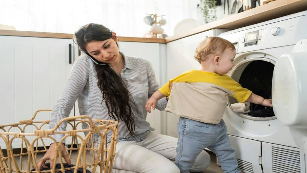 A couple doing the laundry while taking care of her baby