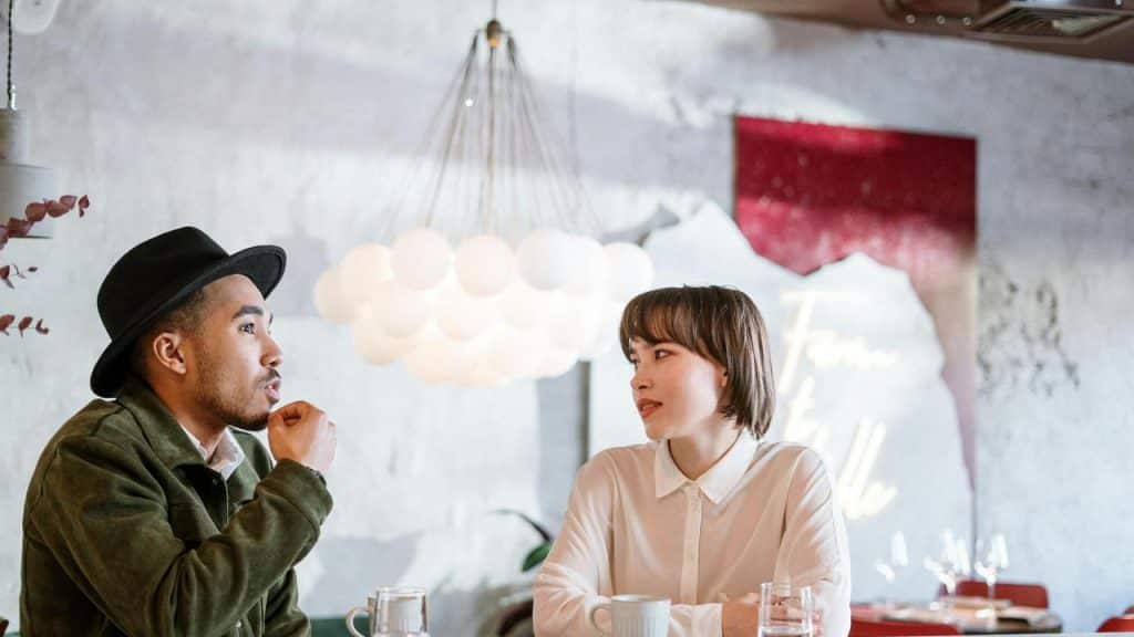 A man and a woman sitting at a café table having a conversation.