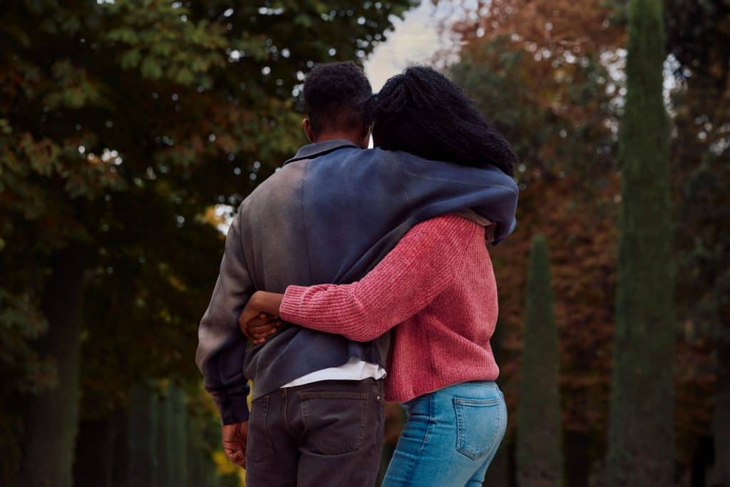 The woman in the pink sweater is hugging the man.