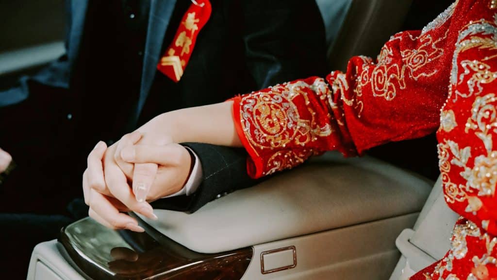 A man holding his wife’s hand while driving.