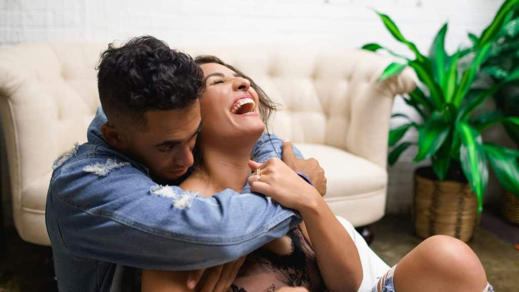 A couple sitting on the floor laughing and hugging.
