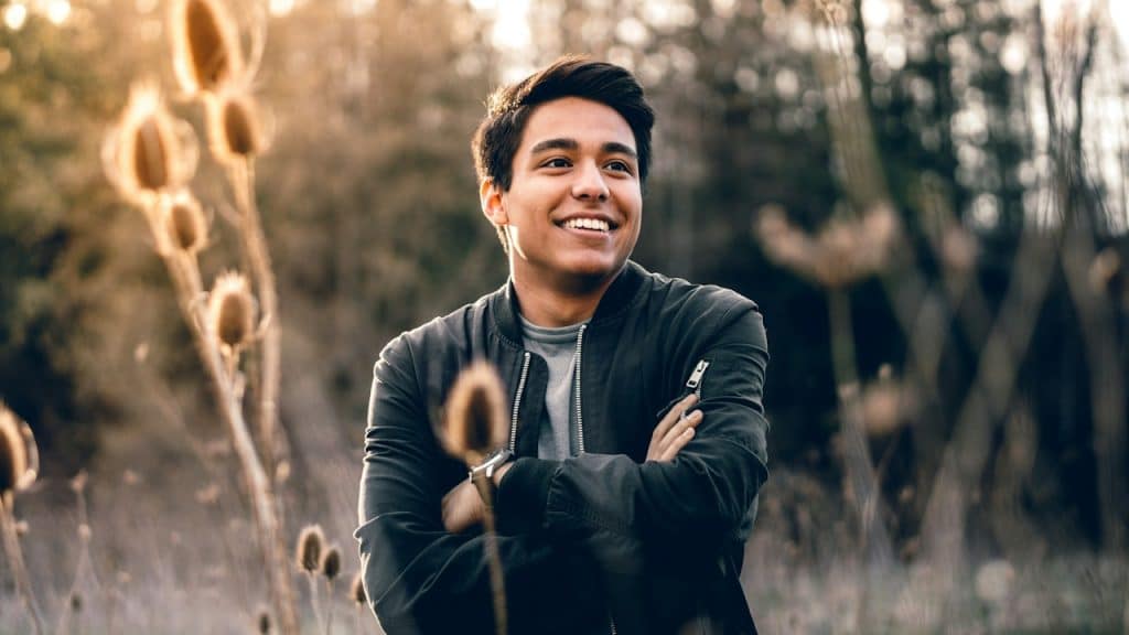 A smiling man standing with his hands crossed outdoors.