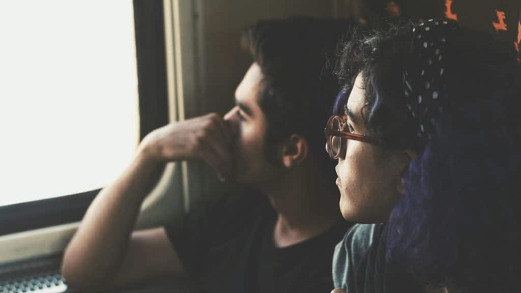 Two people look out of a window on a bus or train.
