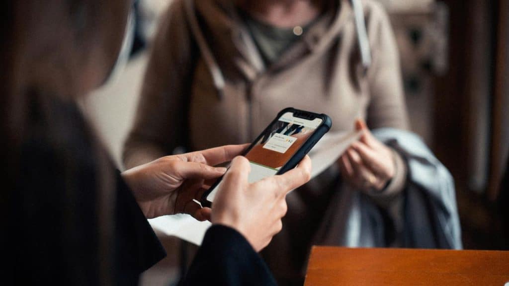 A person holding a smartphone displaying a payment or app screen while sitting at a table.