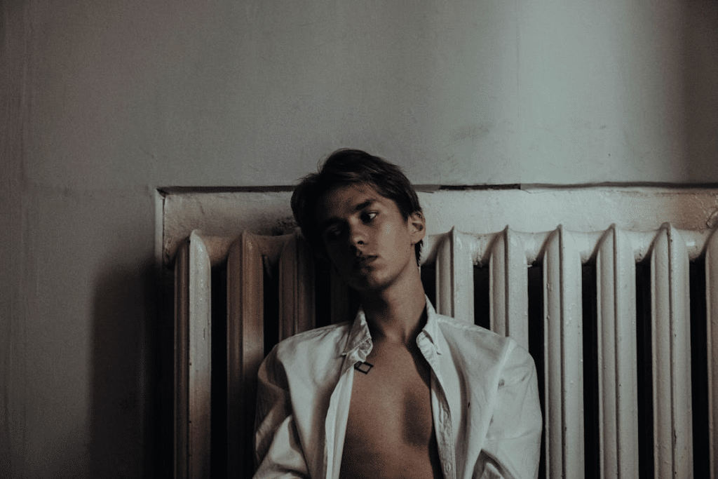 Young Man leaning on a Heater