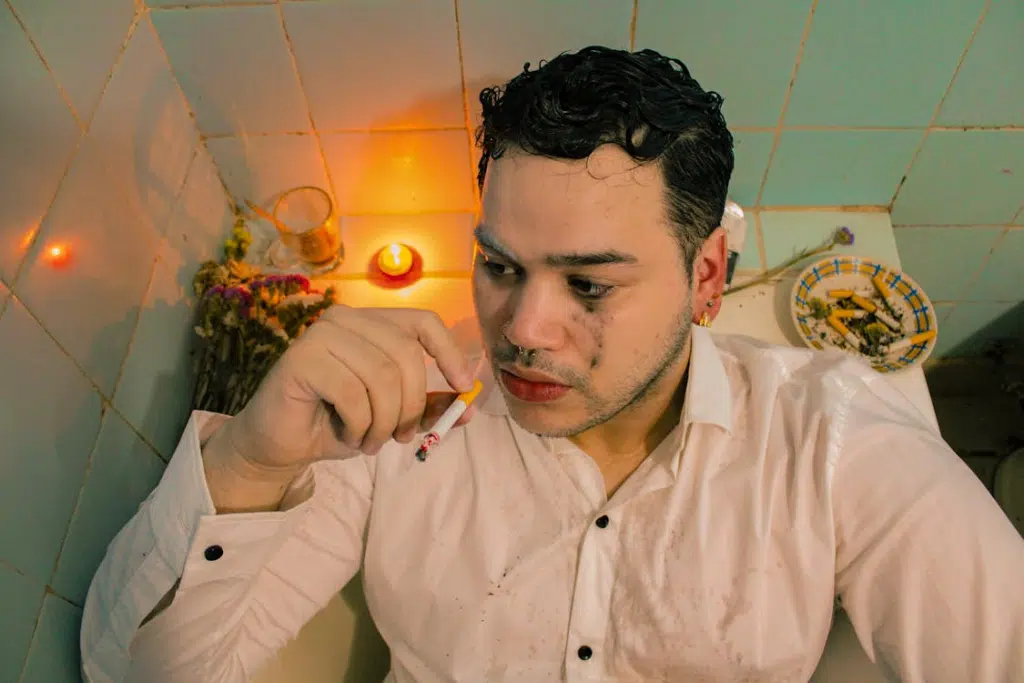 Man in White Shirt Smoking Cigarette in Bathtub