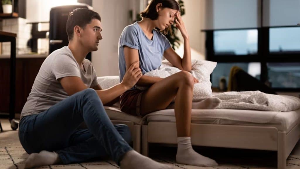 Man quietly sitting beside his partner, looking anxious