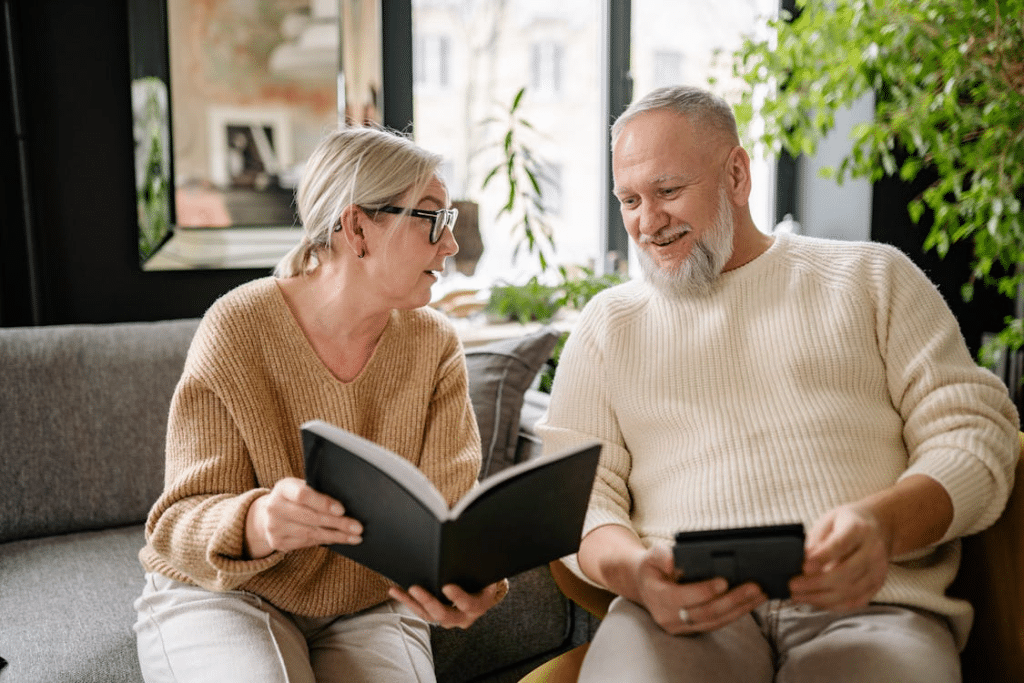 Elderly Couple Reading a Book while Sitting on the Sofa
