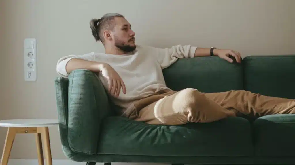 Man sitting alone on a couch with a distant look