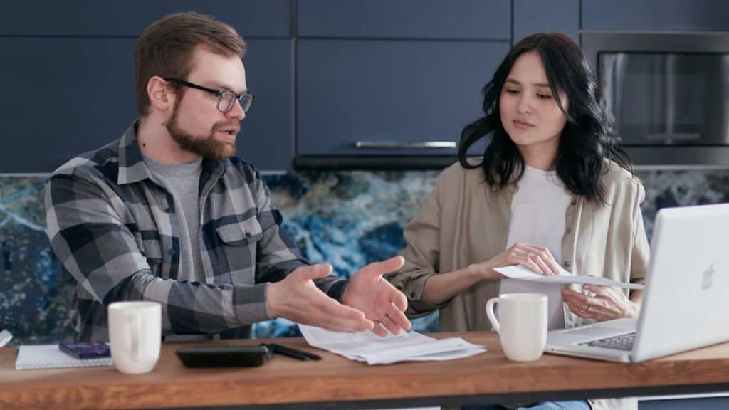 Couple sitting at a kitchen table discussing bills