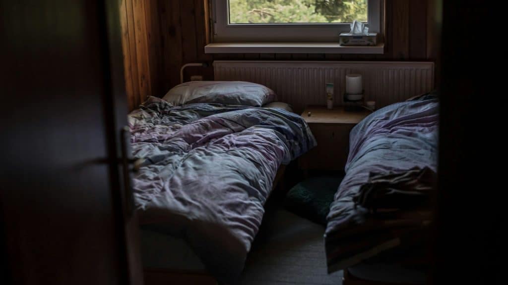 A view of a bedroom with two single beds and a window.