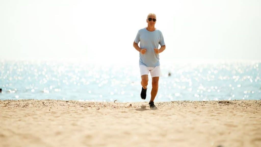 Mature man walking near the ocean at sunrise