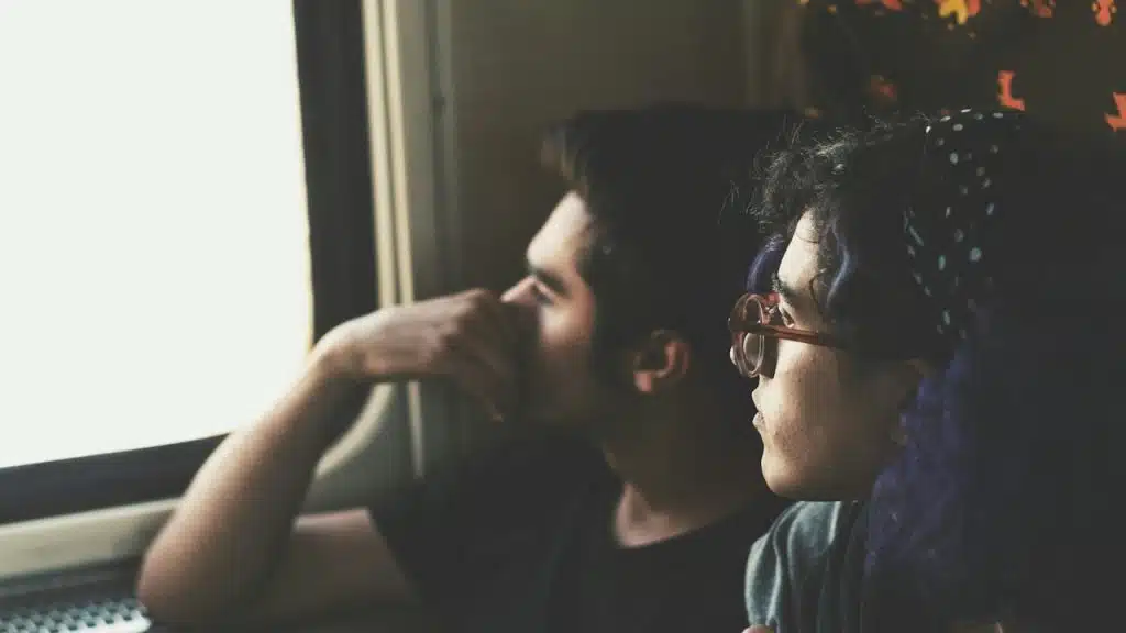 A woman and a man looking out of window.