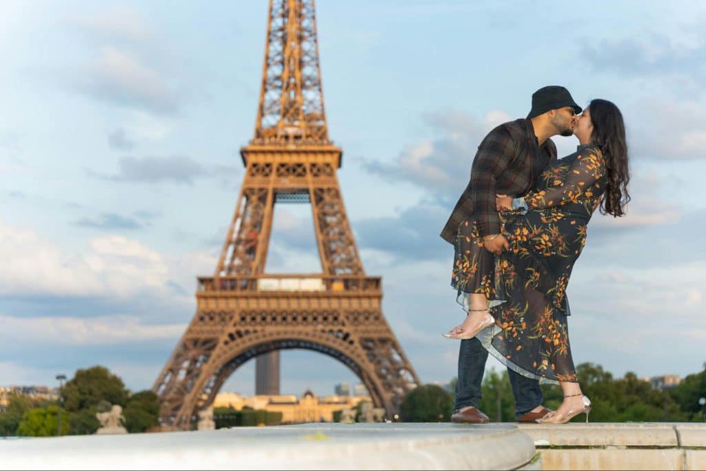 A man and woman kissing in front of eiffel tower