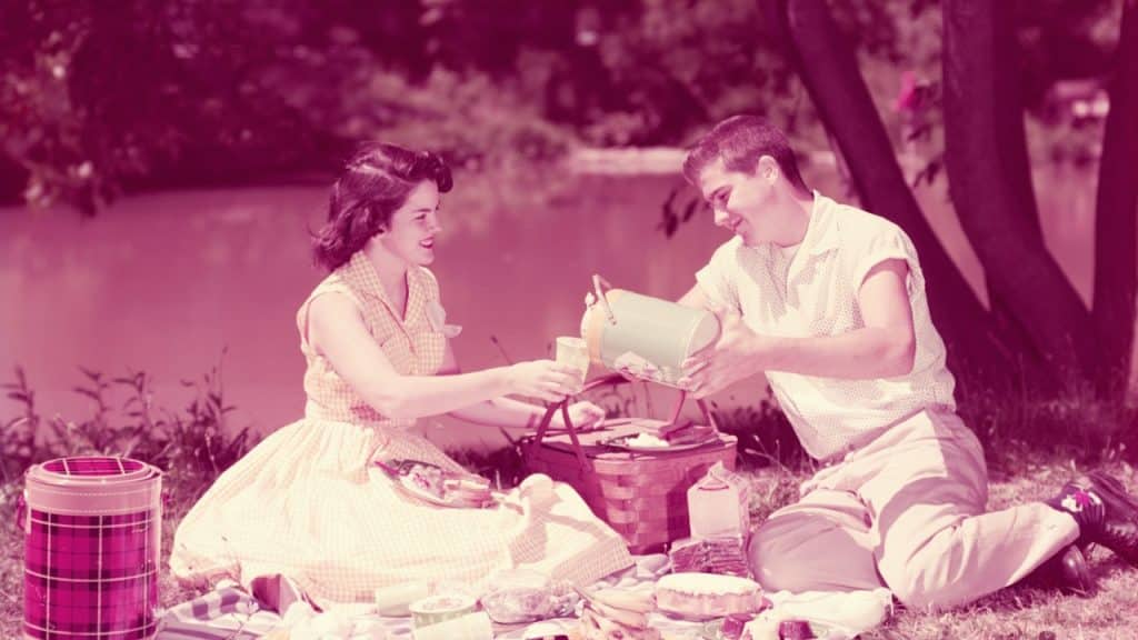 A couple having a summer picnic by a stream.