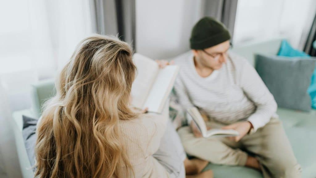 A couple sitting together reading books.