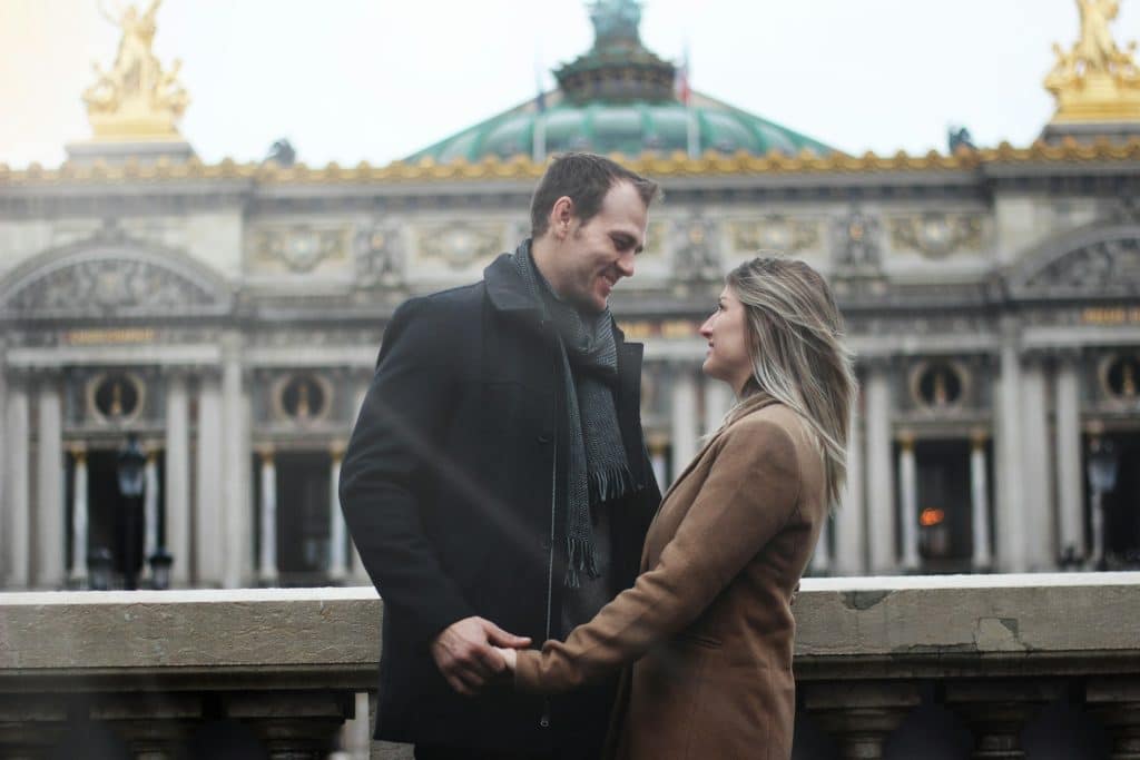 The couple is holding hands while looking at each other.