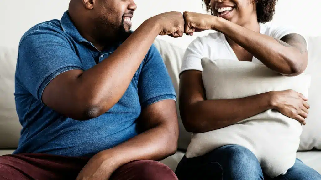 A cheerful Black couple sitting on a sofa.