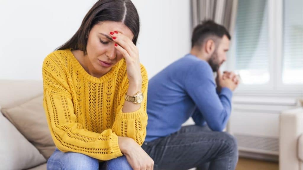 Man and woman sitting apart, both looking frustrated