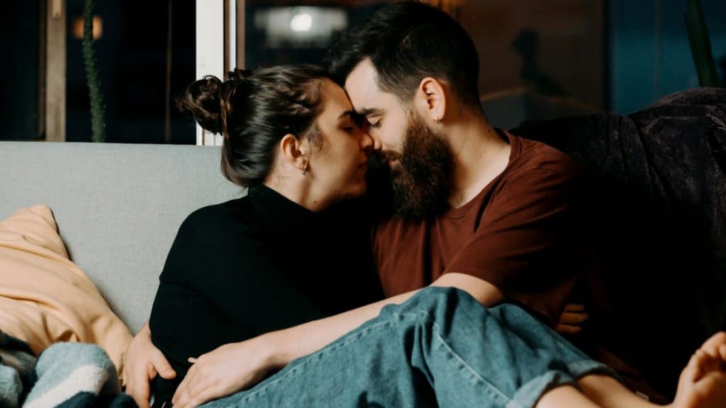 A man and woman embracing each other while sitting on a couch.