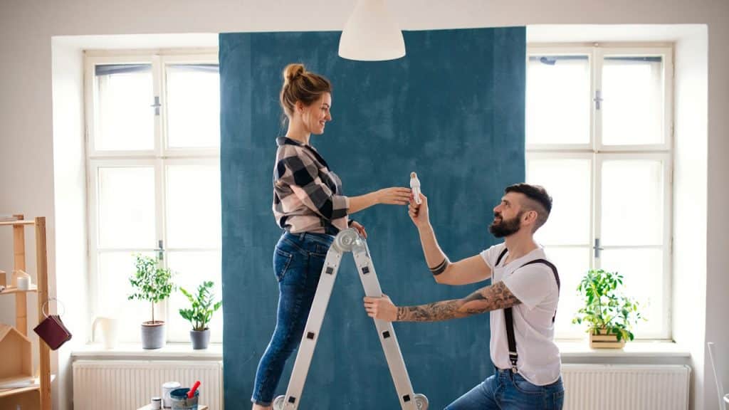 A couple changing a light bulb indoors at home.