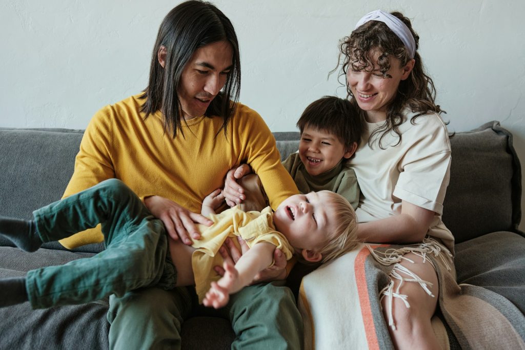 The family is sitting on the couch together.