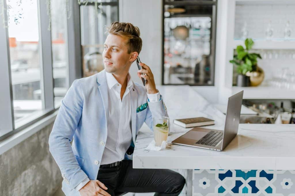 The man is sitting beside a white wooden table.