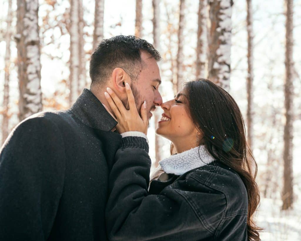 The couple is kissing in the snow.