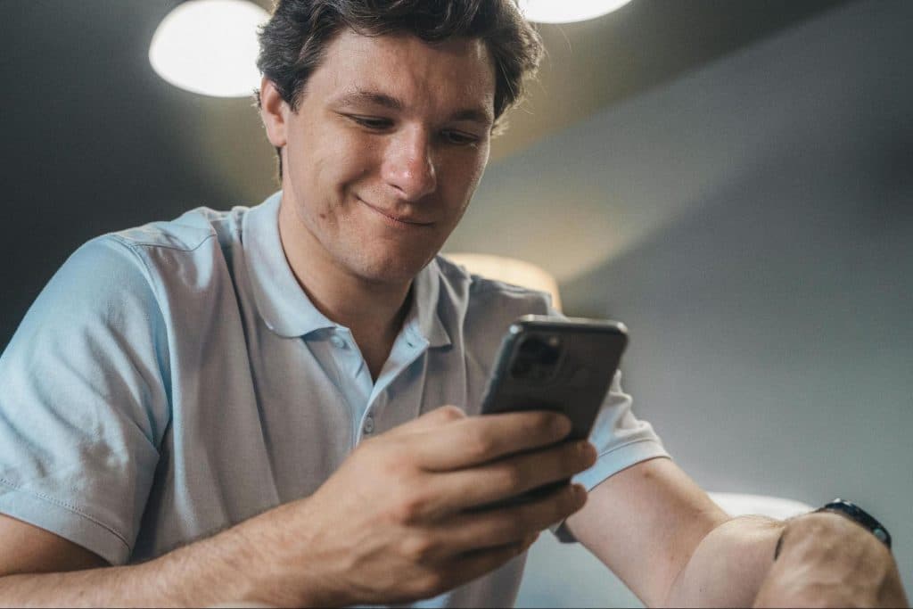 A man smiling while holding phone