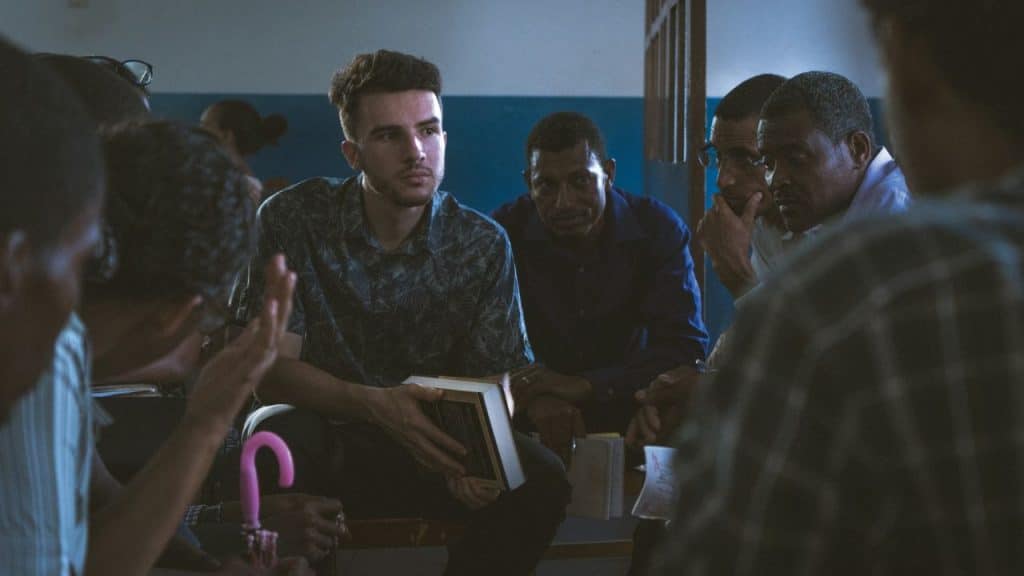 A diverse group of men is sitting in a circle for a serious discussion.