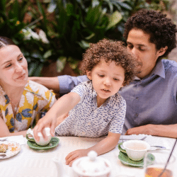 Family with a Little Son Sitting at the Table and Smiling