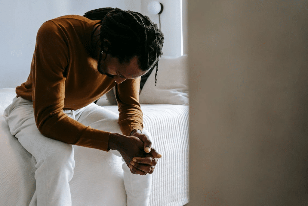 Desperate black man sitting on bed in deep thoughts