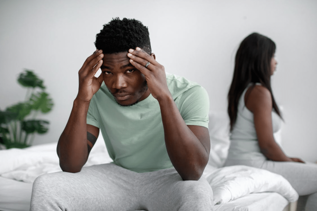 A Man Sitting on the Bed with His Hands on His Head