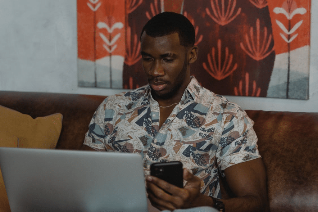 Man in White and Blue Floral Button Up Shirt Holding Black Smartphone