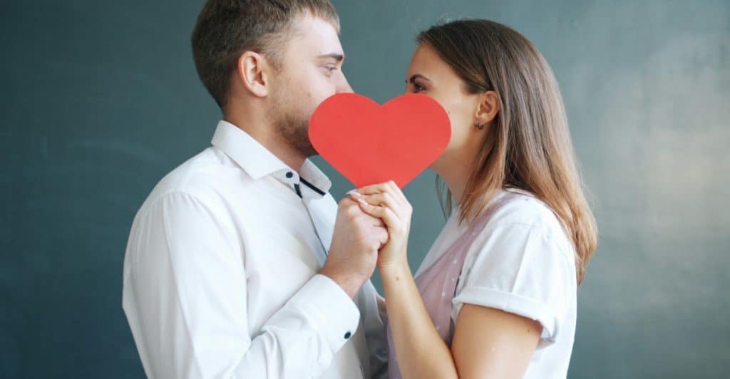 A man and woman holding a heart shaped paper 