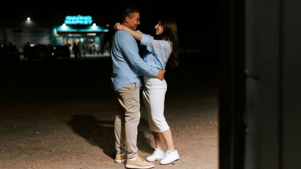 A man and a woman embracing and smiling at each other at night.
