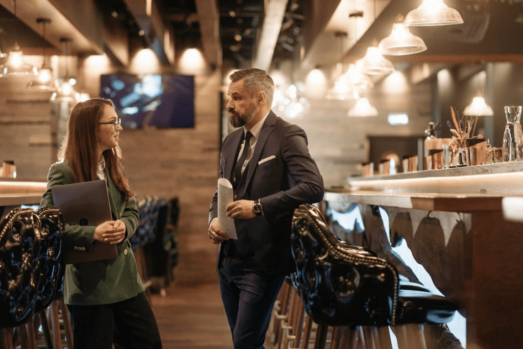 Man in Blue Polo Shirt and Black Pants Standing Beside Woman in White Long Sleeve Shirt
