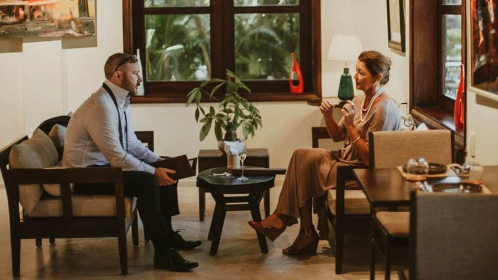 A man and a woman in formal attire talking intently in an indoor setting.