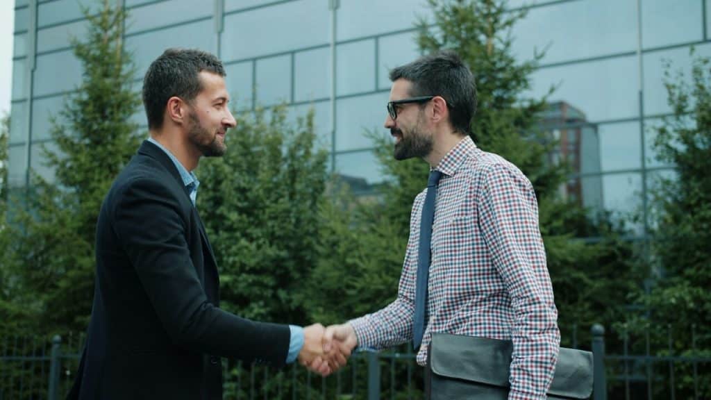 Two colleagues shaking hands outdoors