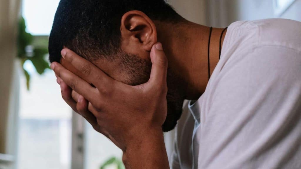 A man sitting with his face in his hands, appearing stressed or upset.