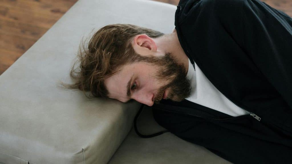 A man lying on a couch, looking tired or thoughtful.