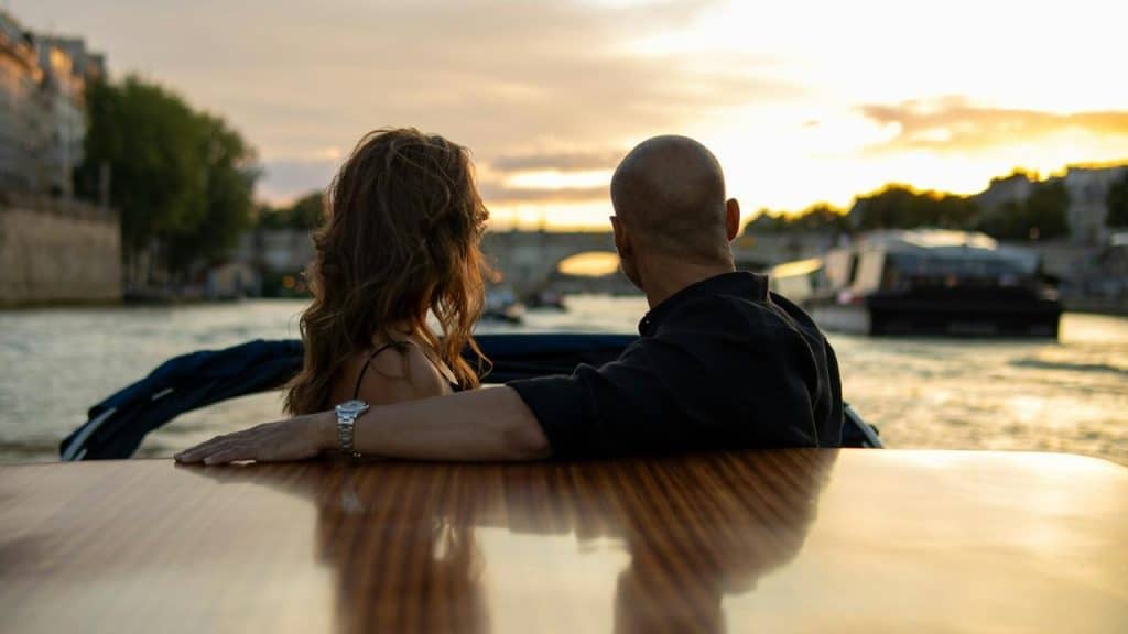 A couple enjoys a peaceful boat ride at sunset on a river.