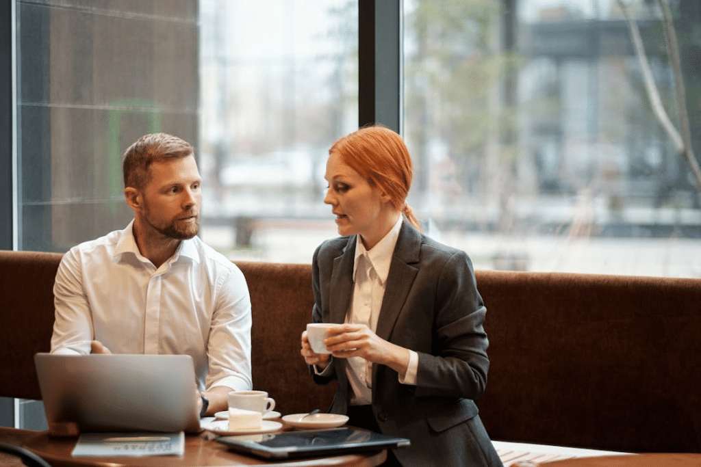 A Man Sitting in Front of a Laptop Beside a Woman in Gray Jacket