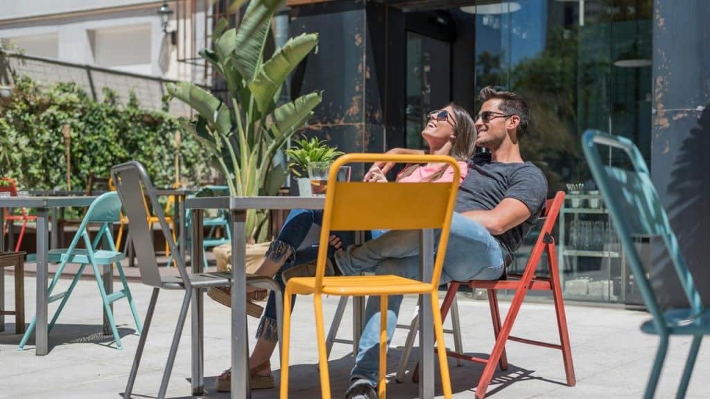 A couple relaxes together at an outdoor café on a sunny day.