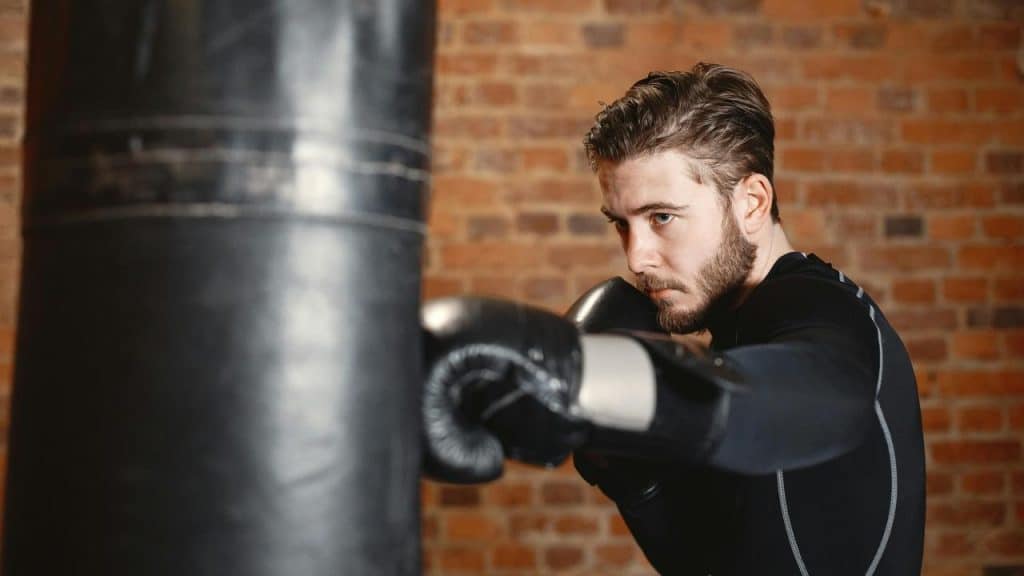 A man wearing boxing gloves trains with a punching bag.