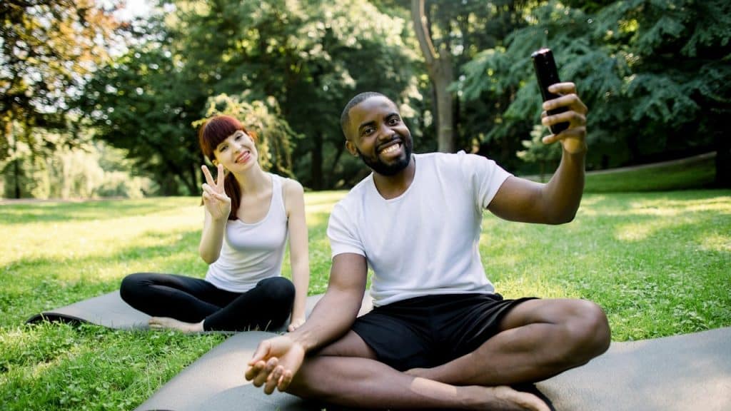 A couple doing yoga together in a park.